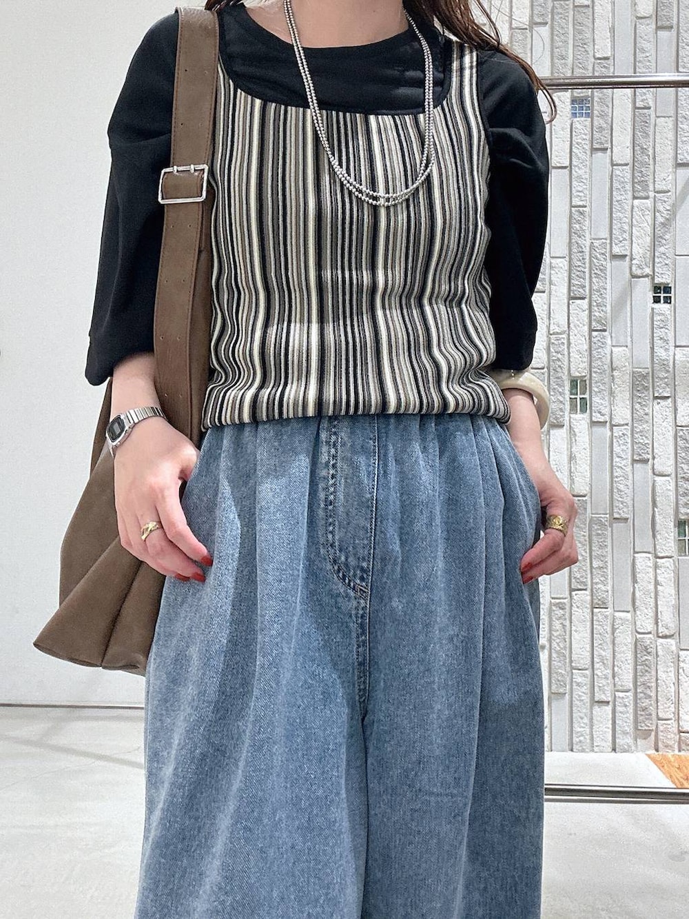 ブルー系のデニムパンツ、ブラック系のサンダル、ブラック系のTシャツ/カットソーを着用したレディースの春コーディネートの4枚目の写真