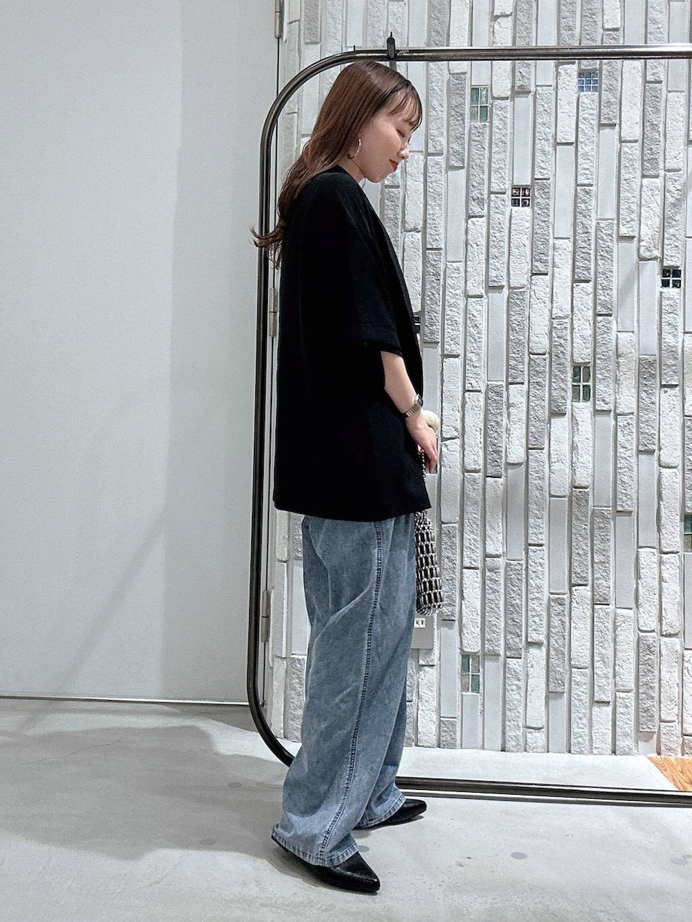 ブルー系のデニムパンツ、ブラック系のテーラードジャケット、シルバー系のショルダーバッグを着用したレディースの春コーディネートの3枚目の写真