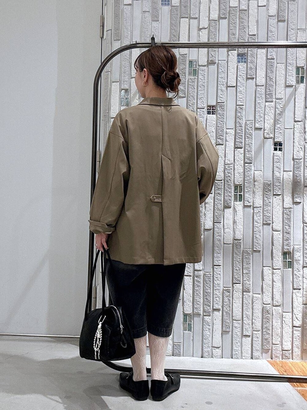 ブラウン系のテーラードジャケット、ブラック系のボストンバッグ、ブラック系のTシャツ/カットソーを着用したレディースの春コーディネートの5枚目の写真