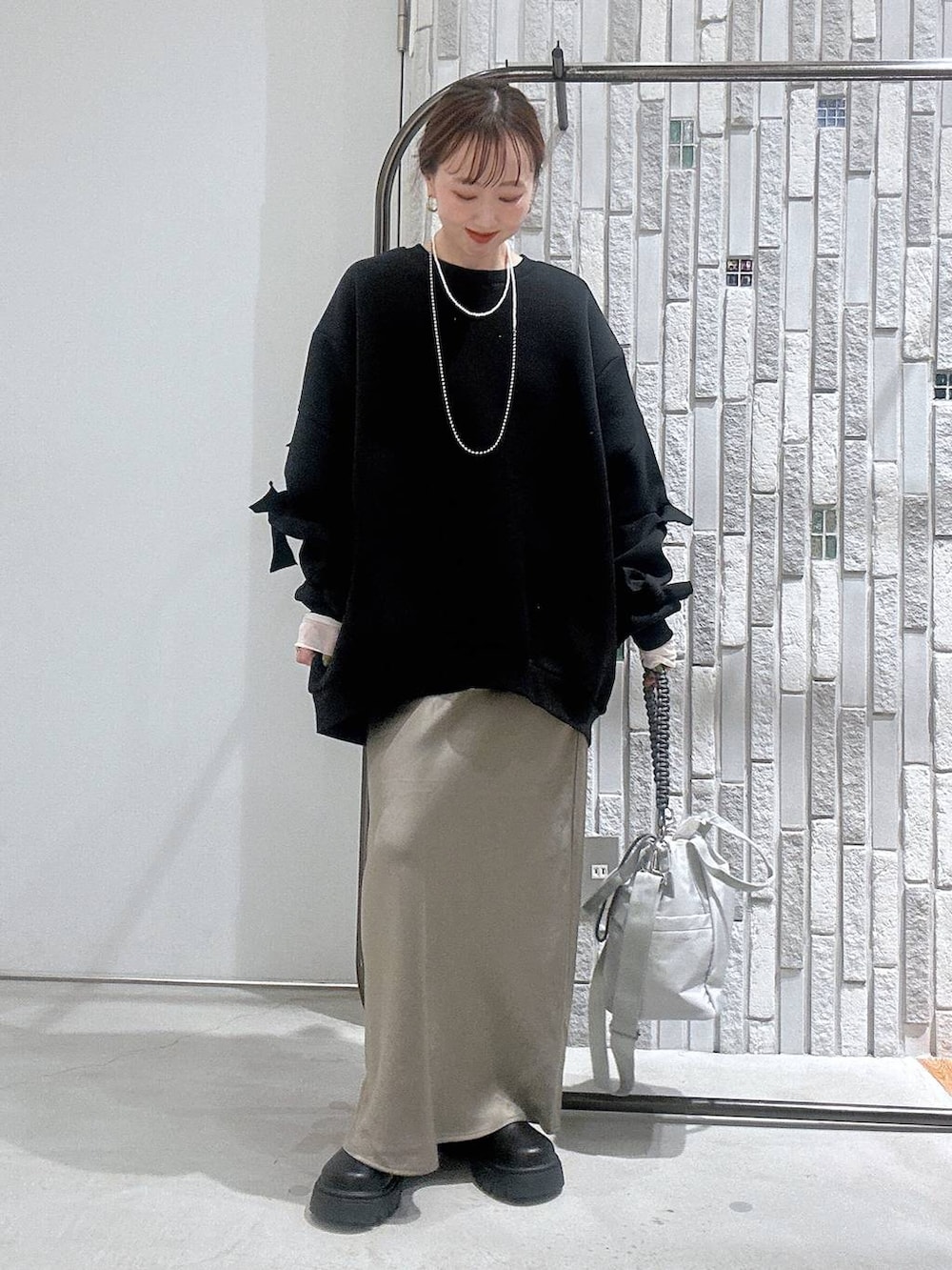 グリーン系のスカート、ブラック系のスウェット、ホワイト系のTシャツ/カットソーを着用したレディースの冬コーディネートの2枚目の写真