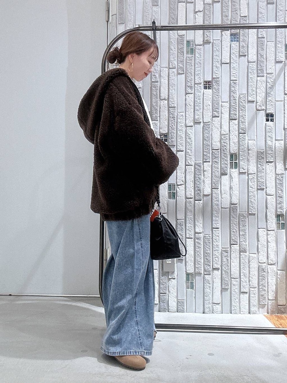 ブラック系のショルダーバッグ、ブルー系のデニムパンツ、ブラウン系のブルゾンを着用したレディースの冬コーディネートの3枚目の写真