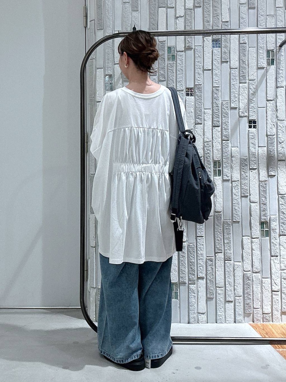 ブルー系のデニムパンツ、ブラック系のサンダル、グレー系のバックパック/リュックを着用したレディースの春コーディネートの3枚目の写真