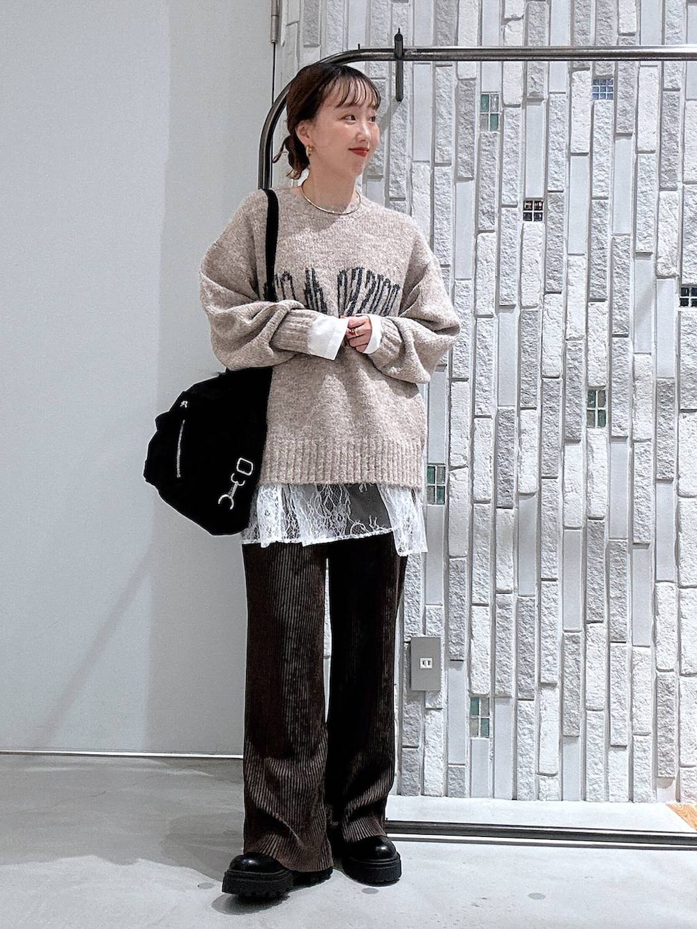 ホワイト系のTシャツ/カットソー、ベージュ系のニット/セーター、ブラック系のブーツを着用したレディースの冬コーディネートの2枚目の写真