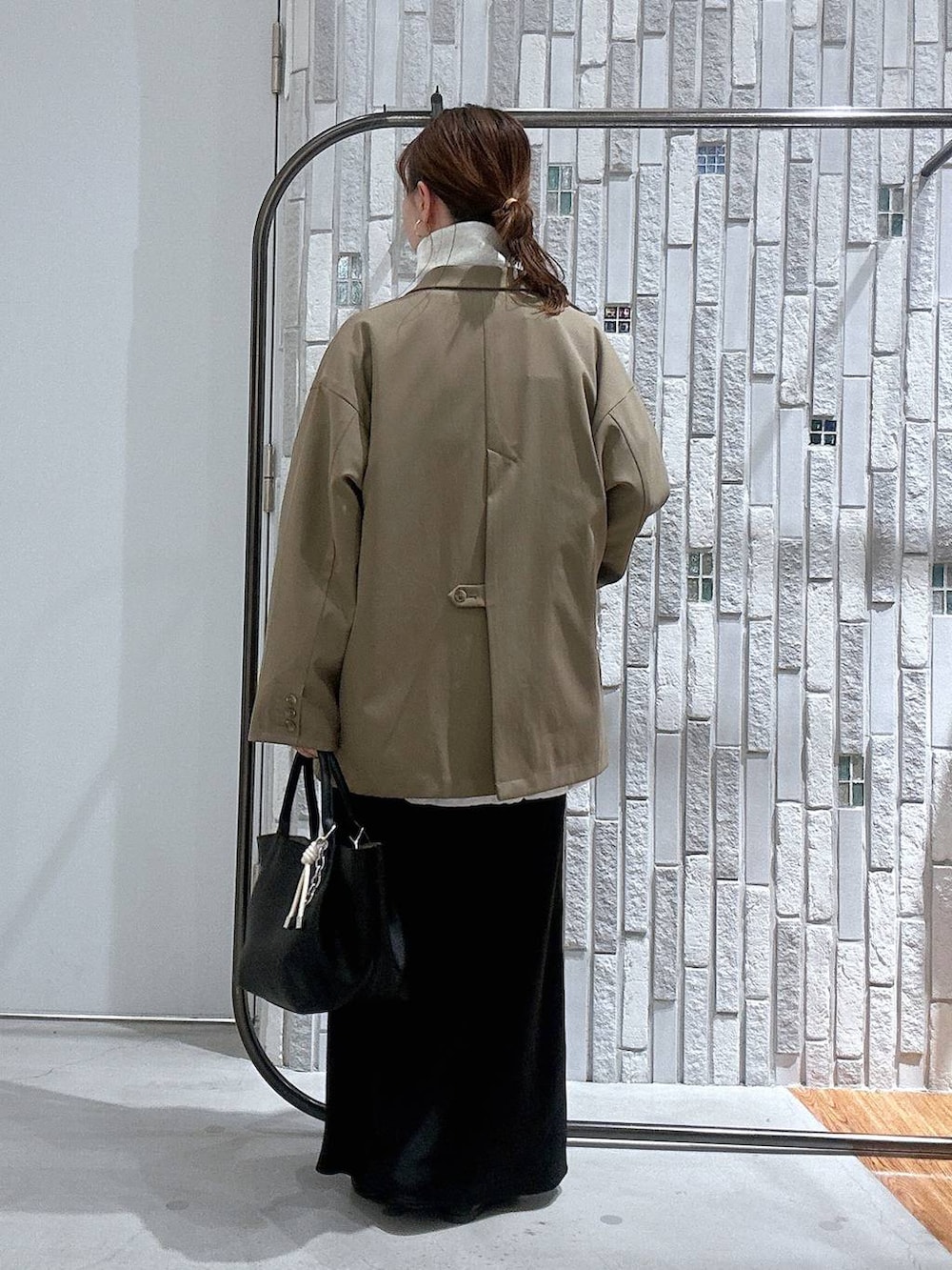 ブラック系のスカート、ブラウン系のテーラードジャケット、ブラック系のトートバッグを着用したレディースの冬コーディネートの4枚目の写真