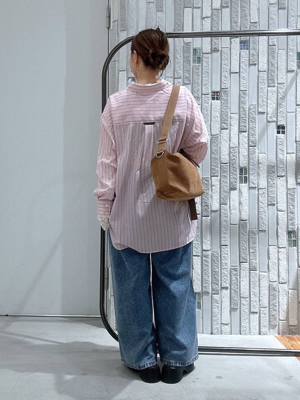 ブラウン系のショルダーバッグ、ブラウン系のサンダル、ブルー系のデニムパンツを着用したレディースの冬コーディネートの4枚目の写真