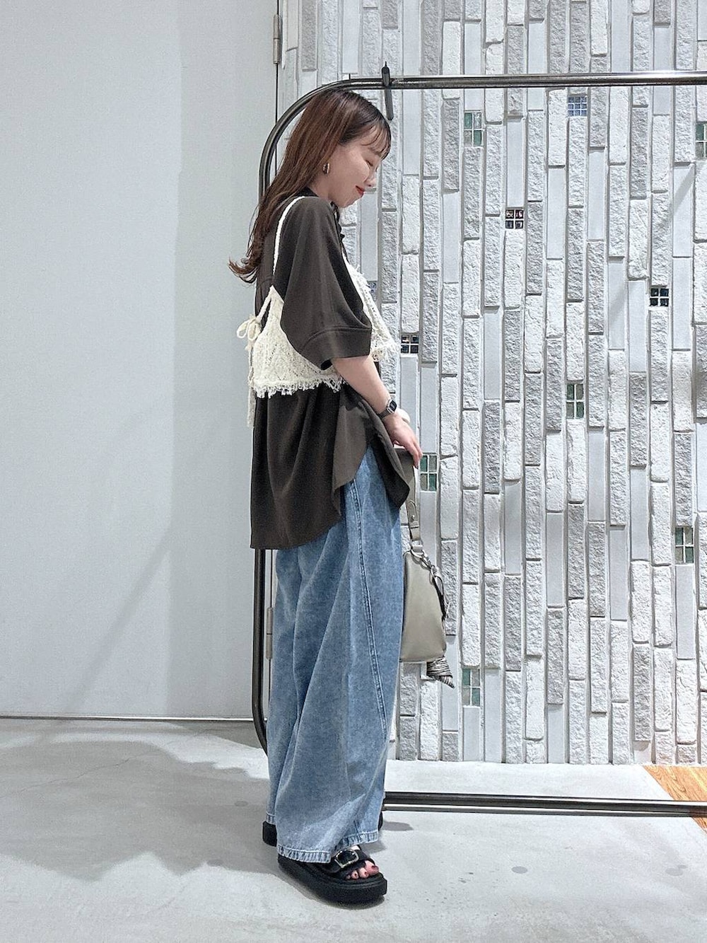 ブルー系のデニムパンツ、ブラック系のサンダル、ベージュ系のショルダーバッグを着用したレディースの春コーディネートの3枚目の写真