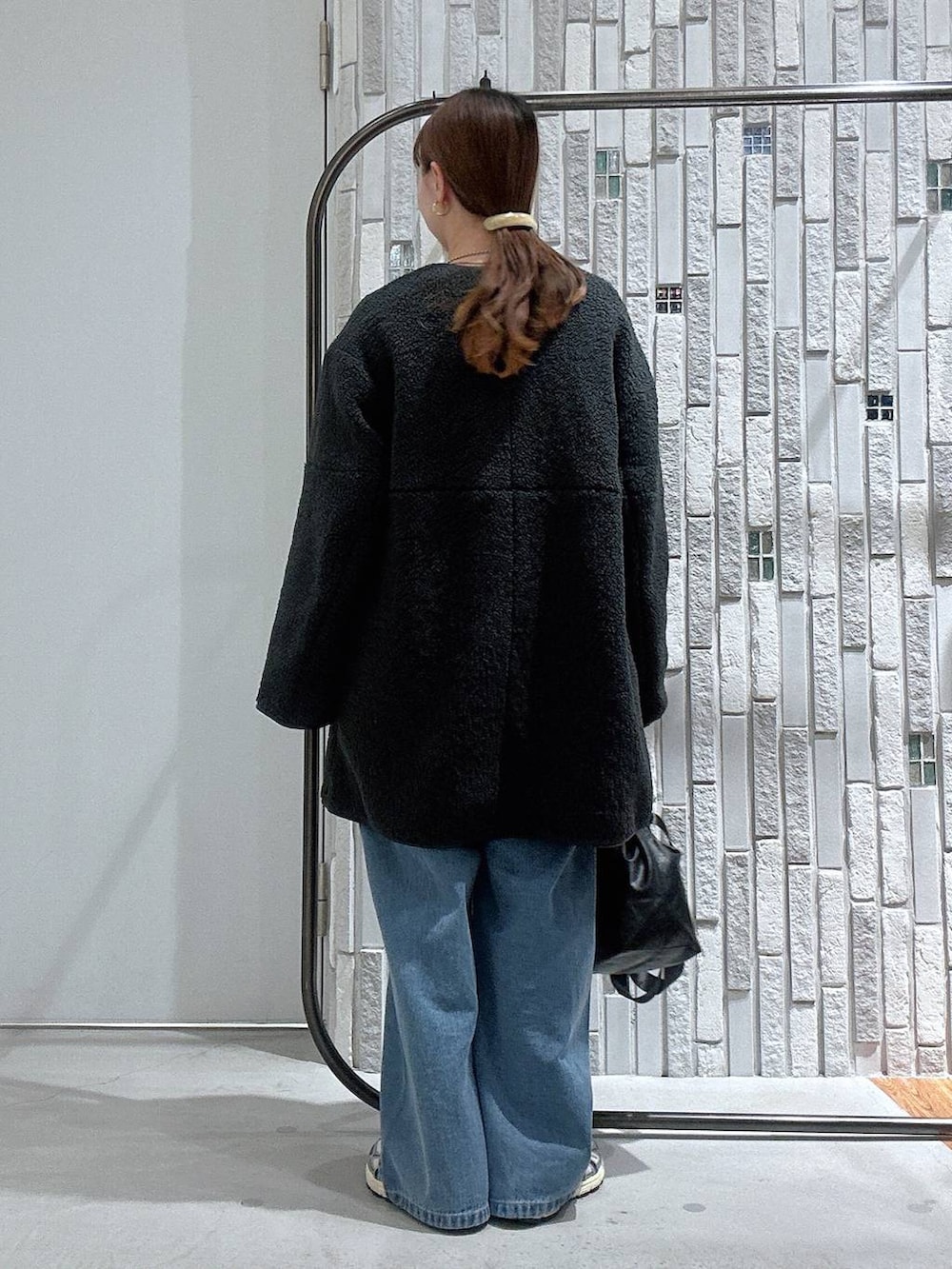 ブラック系のショルダーバッグ、グレー系のその他アウター、ブルー系のデニムパンツを着用したレディースの冬コーディネートの4枚目の写真