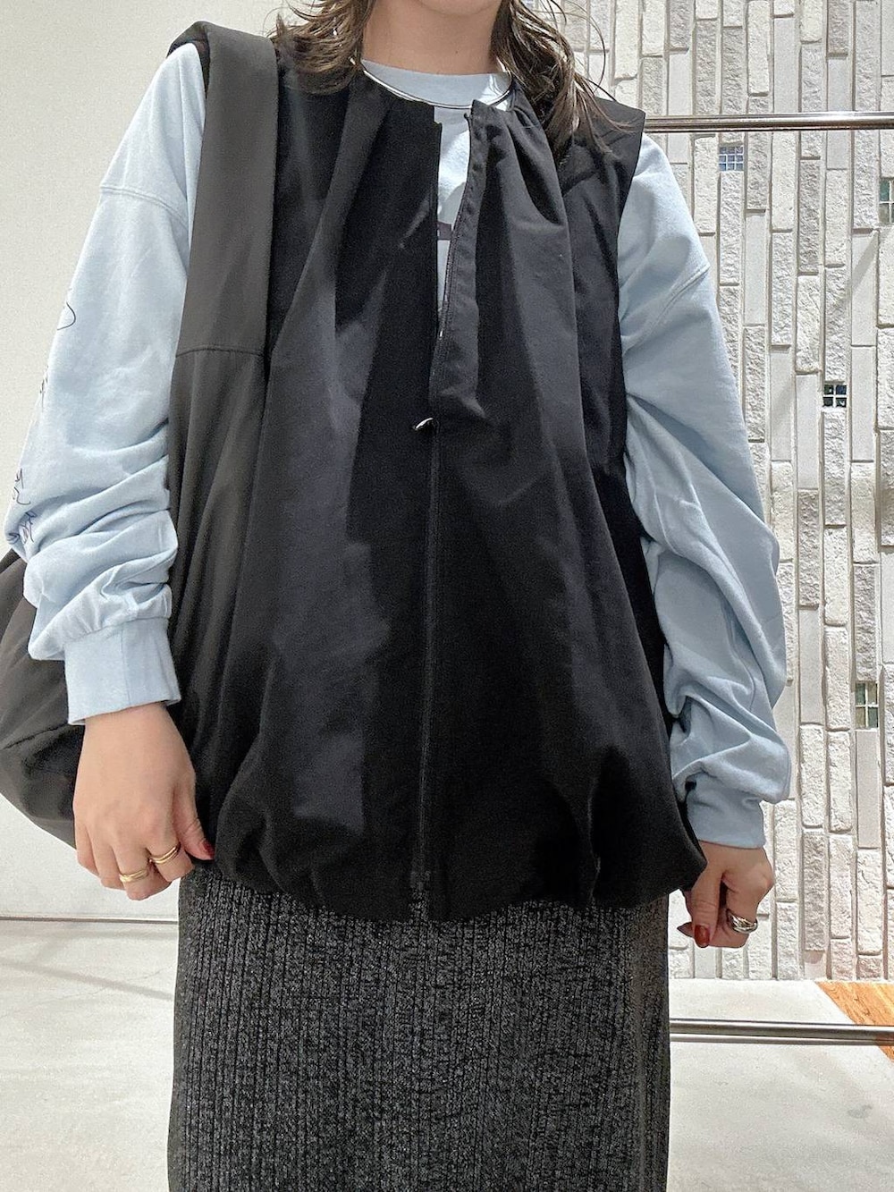 ブルー系のTシャツ/カットソー、グレー系のショルダーバッグ、ブラック系のベストを着用したレディースの秋コーディネートの5枚目の写真