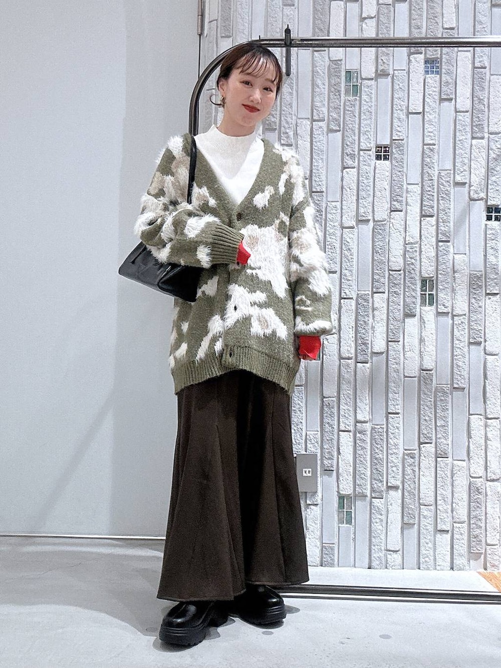 ホワイト系のニット/セーター、ブラック系のボストンバッグ、ブラック系のブーツを着用したレディースの冬コーディネートの2枚目の写真