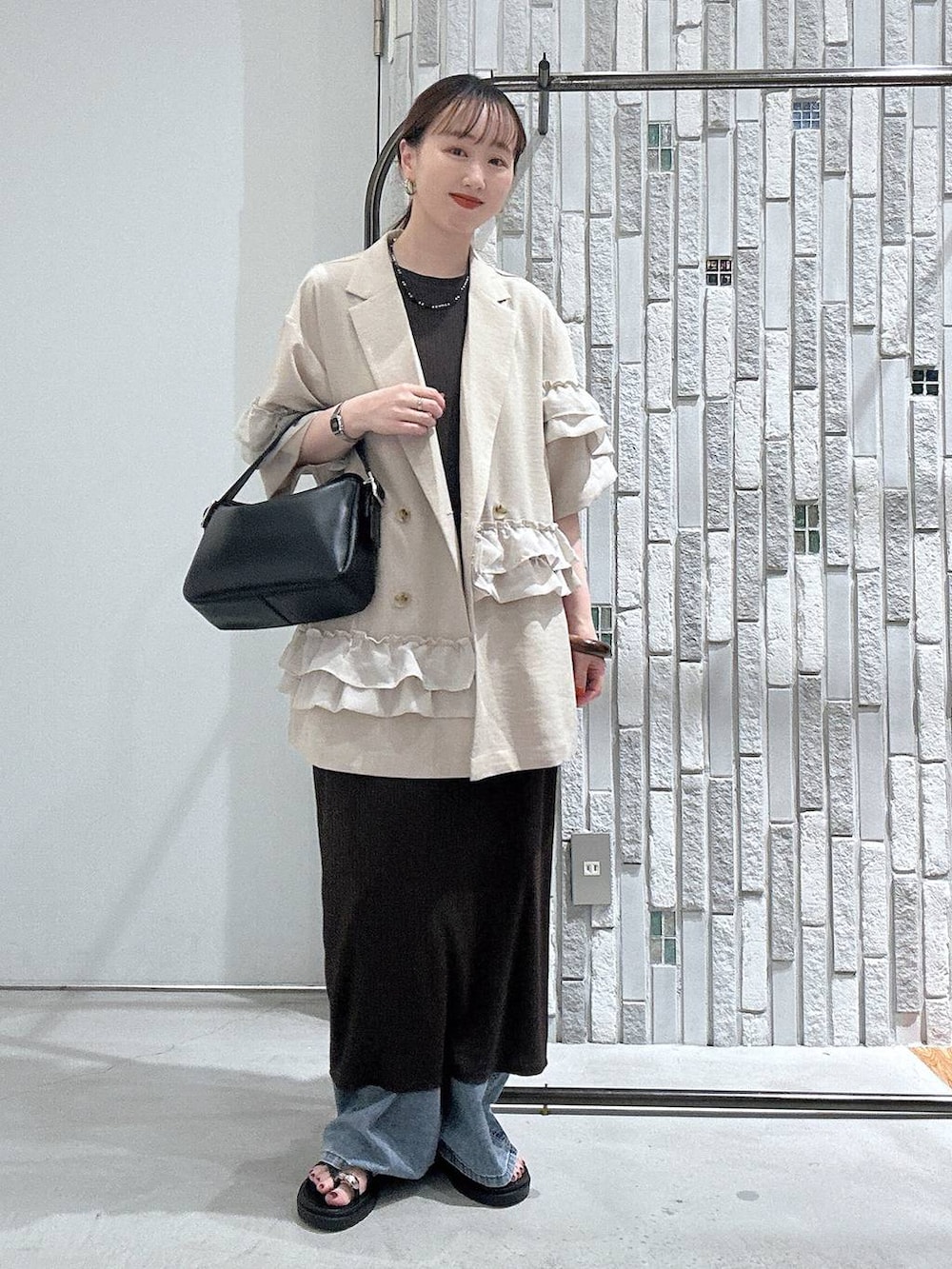 ブルー系のデニムパンツ、ブラック系のサンダル、ブラック系のショルダーバッグを着用したレディースの春コーディネートの2枚目の写真