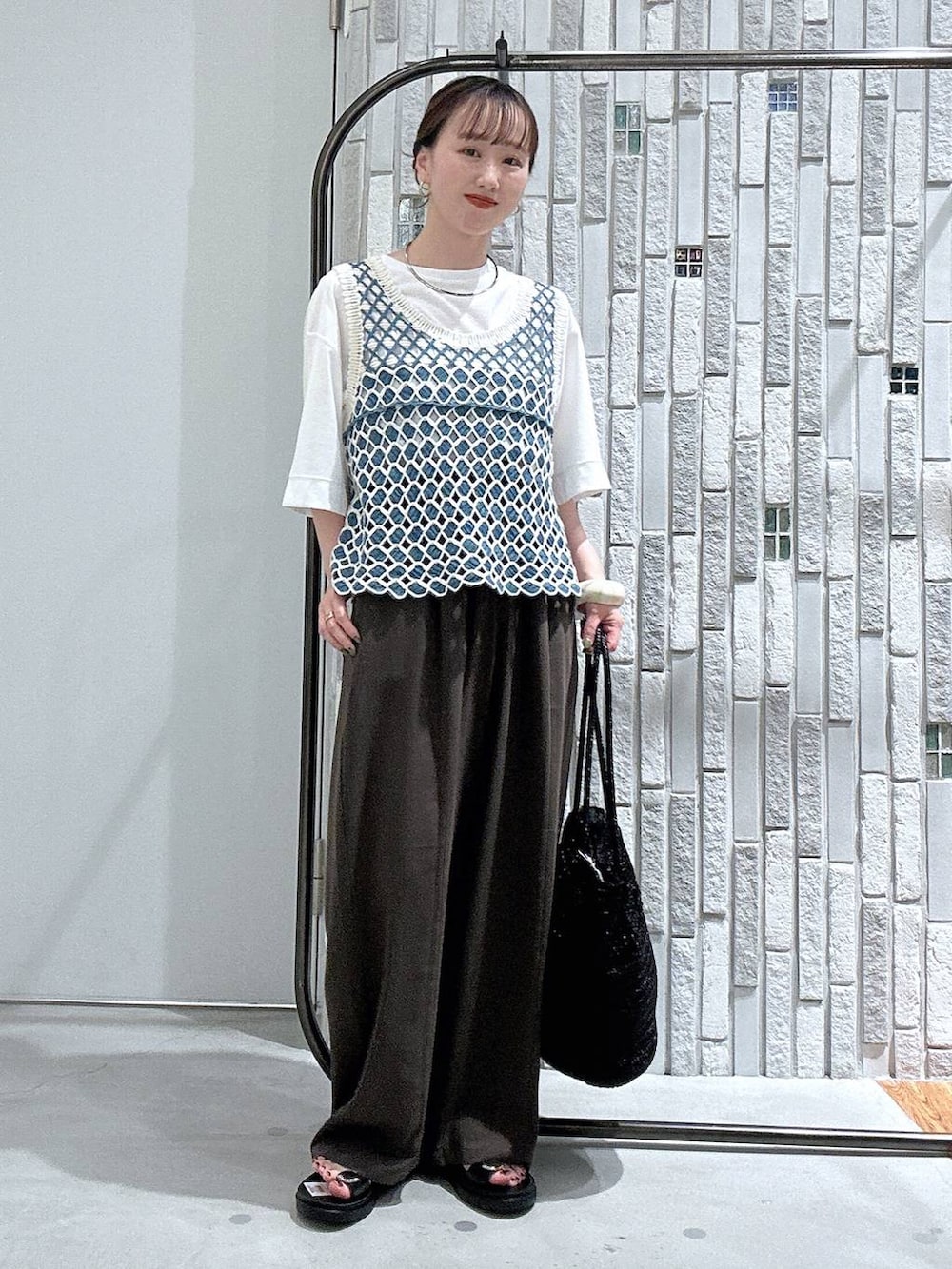 ブラウン系のその他パンツ、ブラック系のサンダル、ホワイト系のTシャツ/カットソーを着用したレディースの春コーディネートの2枚目の写真