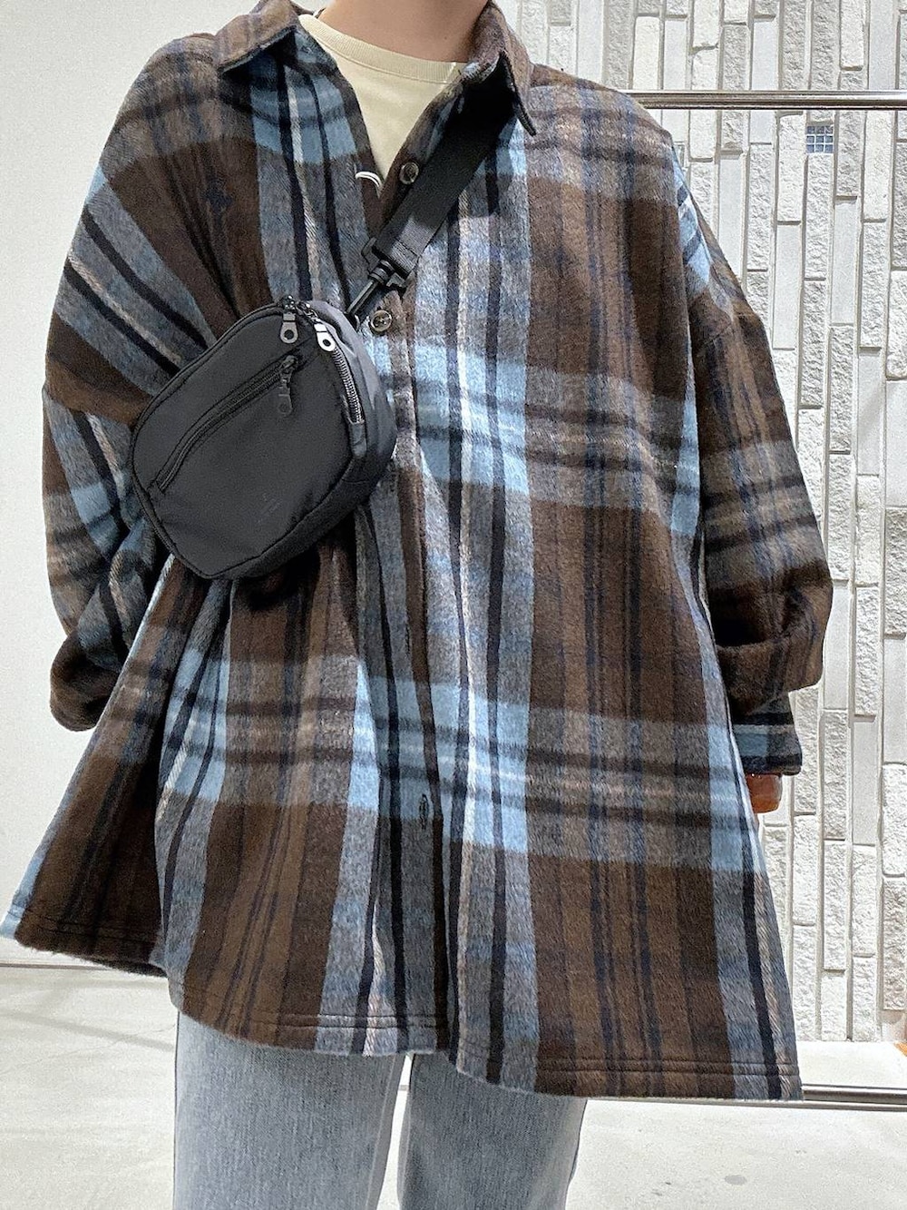 ブルー系のデニムパンツ、ブラック系のボディバッグ/ウエストポーチ、ブラウン系のシャツ/ブラウスを着用したレディースの秋コーディネートの4枚目の写真