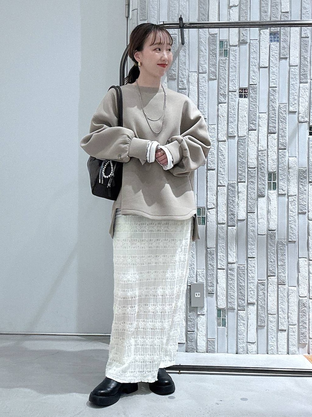 ブラック系のサンダル、ブラウン系のボストンバッグ、ブラウン系のスウェットを着用したレディースの冬コーディネートの2枚目の写真