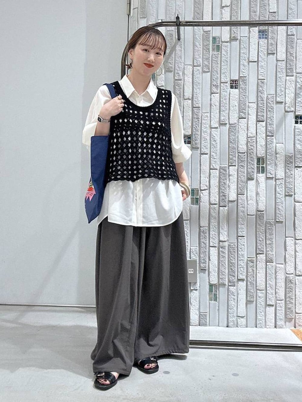 ブラック系のベスト、ブラック系のサンダル、ホワイト系のシャツ/ブラウスを着用したレディースの夏コーディネートの2枚目の写真