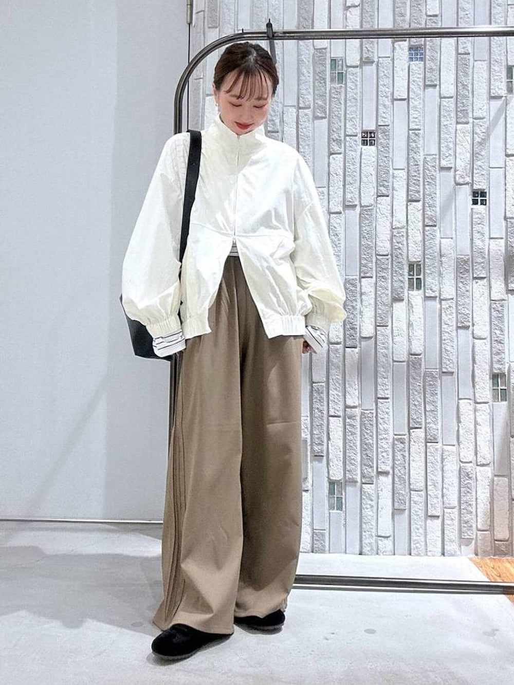 ブラック系のショルダーバッグ、ブラウン系のその他パンツ、ホワイト系のブルゾンを着用したレディースの冬コーディネートの2枚目の写真