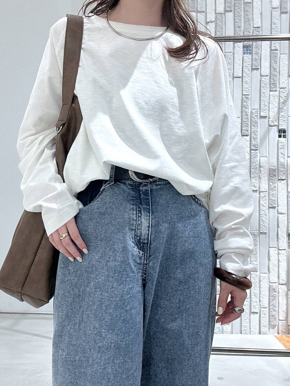 ブルー系のデニムパンツ、ブラウン系のショルダーバッグ、ホワイト系のTシャツ/カットソーを着用したレディースの春コーディネートの4枚目の写真