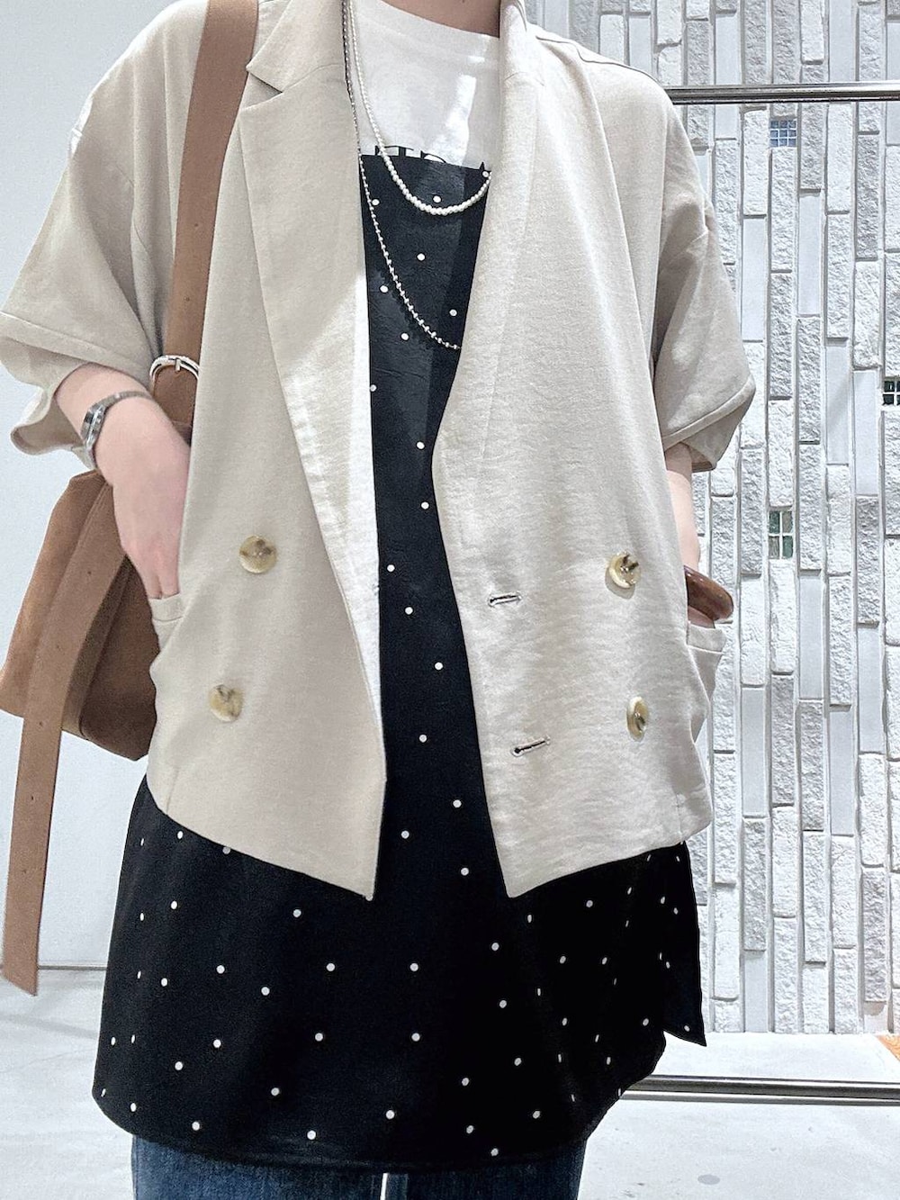 ブラウン系のショルダーバッグ、ブルー系のデニムパンツ、ベージュ系のテーラードジャケットを着用したレディースの春コーディネートの5枚目の写真