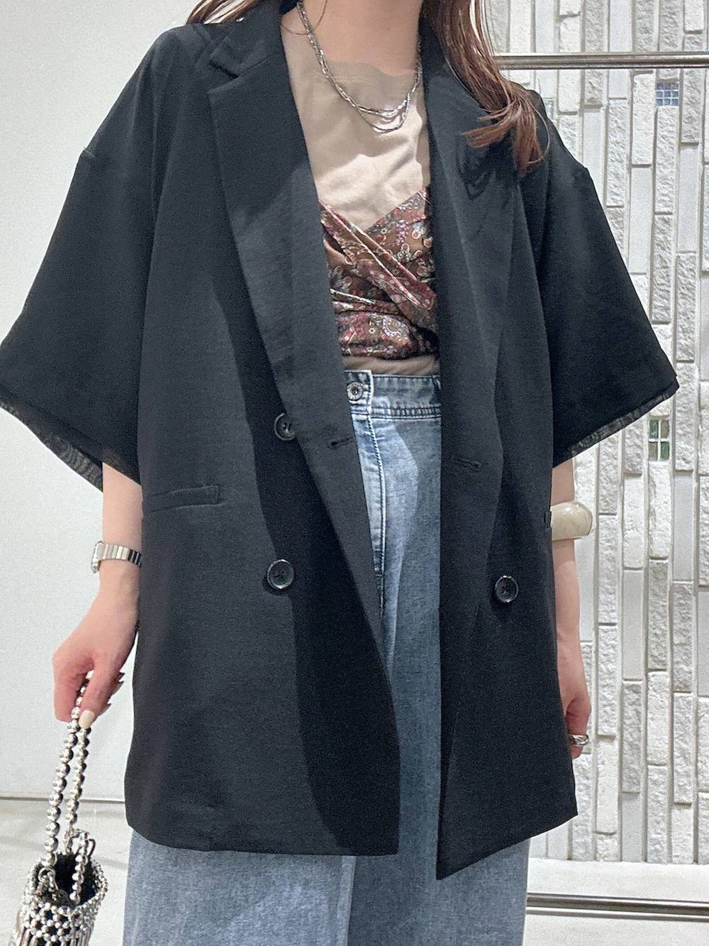 ブルー系のデニムパンツ、ブラック系のテーラードジャケット、シルバー系のショルダーバッグを着用したレディースの春コーディネートの5枚目の写真