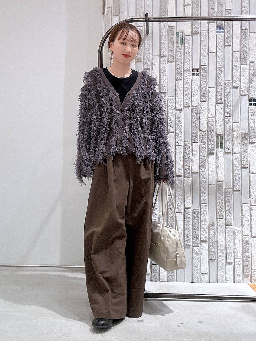 ブラック系のブーツ、ブラック系のTシャツ/カットソー、ホワイト系のボストンバッグを着用したレディースの冬コーディネートの2枚目の写真