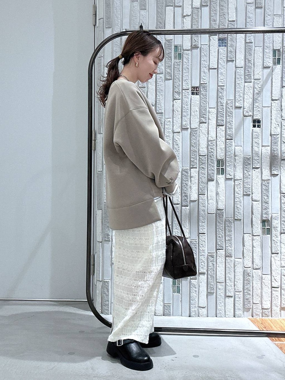 ブラック系のサンダル、ブラウン系のボストンバッグ、ブラウン系のスウェットを着用したレディースの冬コーディネートの3枚目の写真