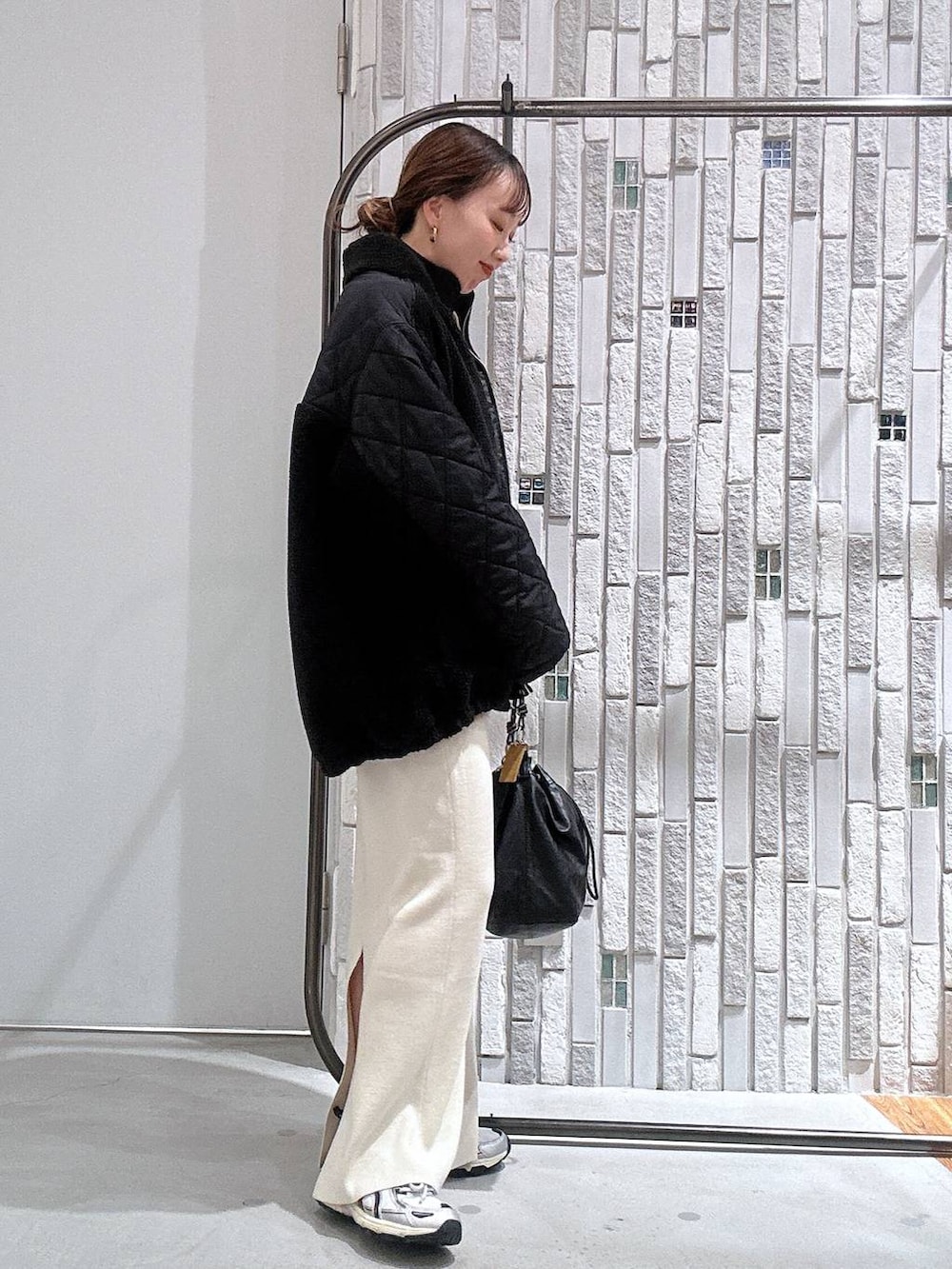ブラック系のショルダーバッグ、ホワイト系のスカート、ブラック系のブルゾンを着用したレディースの冬コーディネートの3枚目の写真