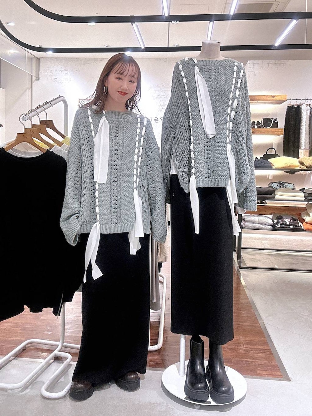 ブラック系のスカート、ブラウン系のブーツ、グリーン系のニット/セーターを着用したレディースの冬コーディネートの2枚目の写真