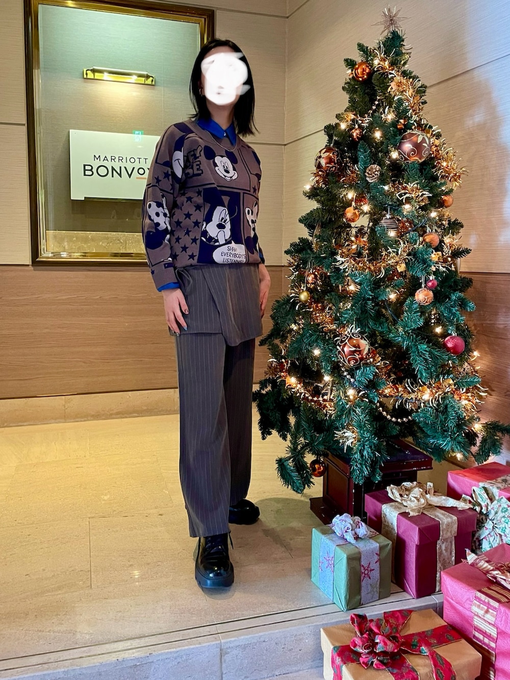 グレー系のニット/セーター、ブルー系のシャツ/ブラウス、グレー系のスラックスを着用したレディースの冬コーディネートの2枚目の写真