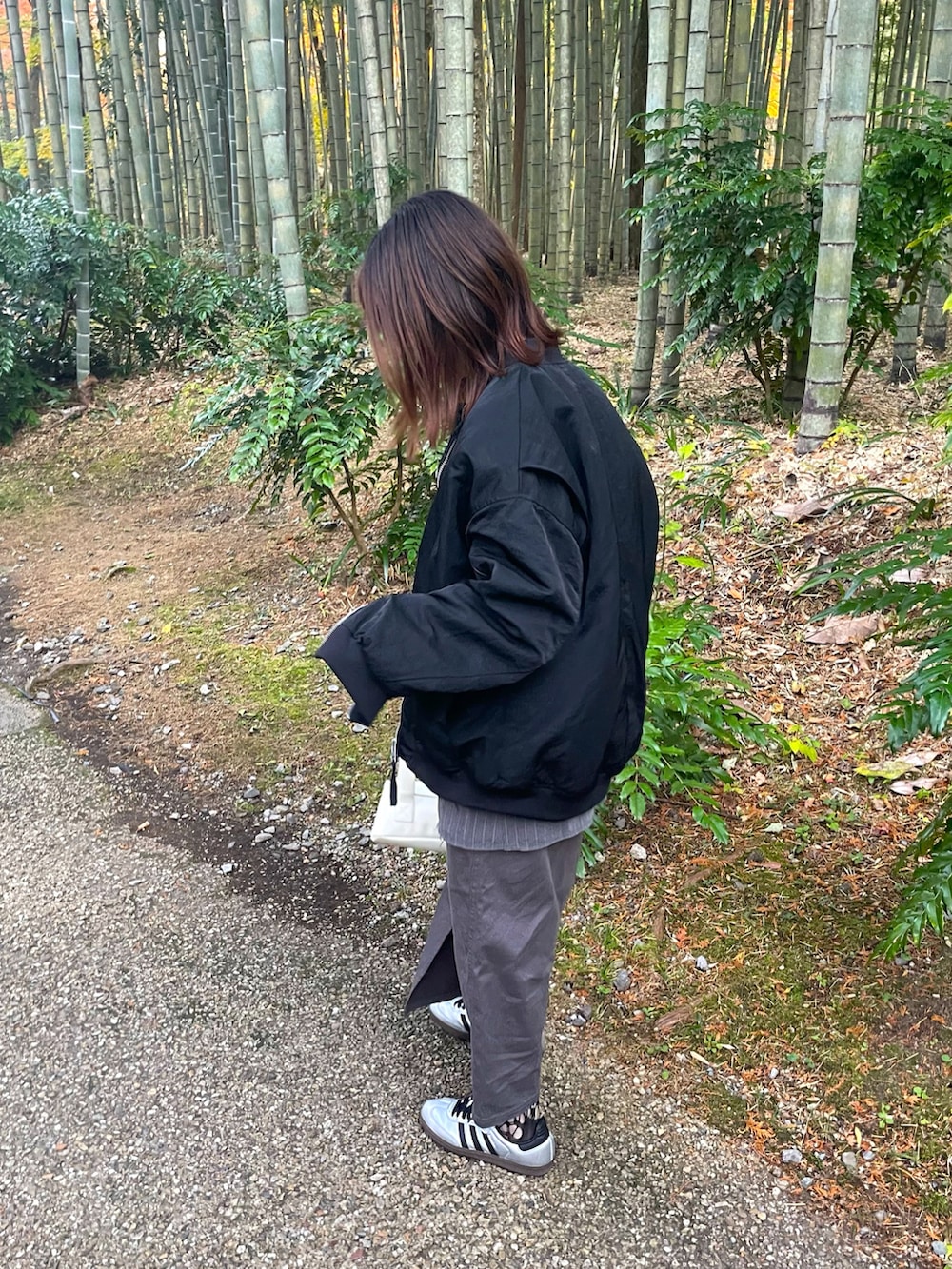 ブラック系のMA-1、シルバー系のトップス、グレー系のスラックスを着用したレディースの冬コーディネートの3枚目の写真