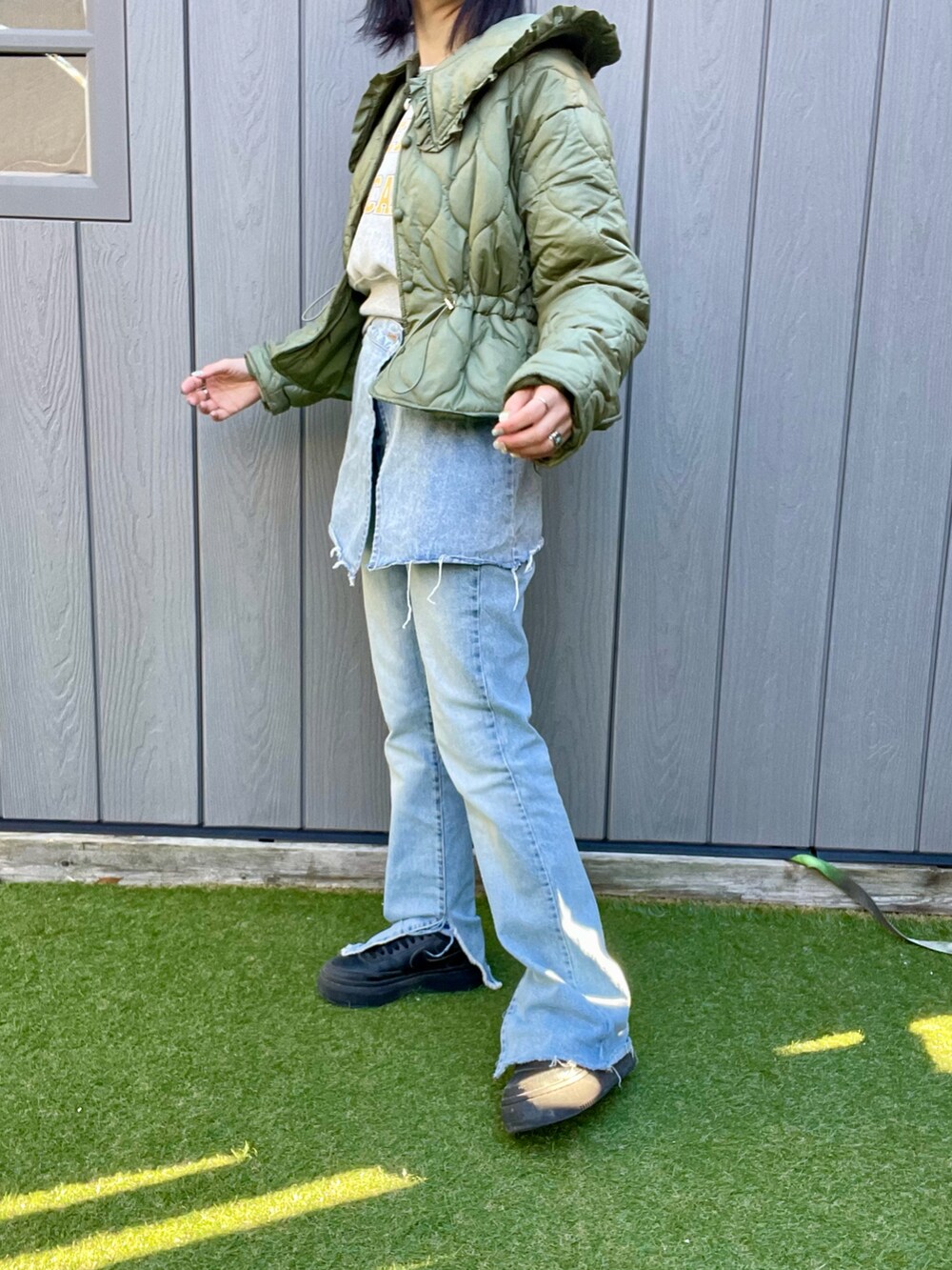 ブルー系のデニムパンツ、ブラック系のスニーカー、グリーン系のその他アウターを着用したレディースの冬コーディネートの2枚目の写真