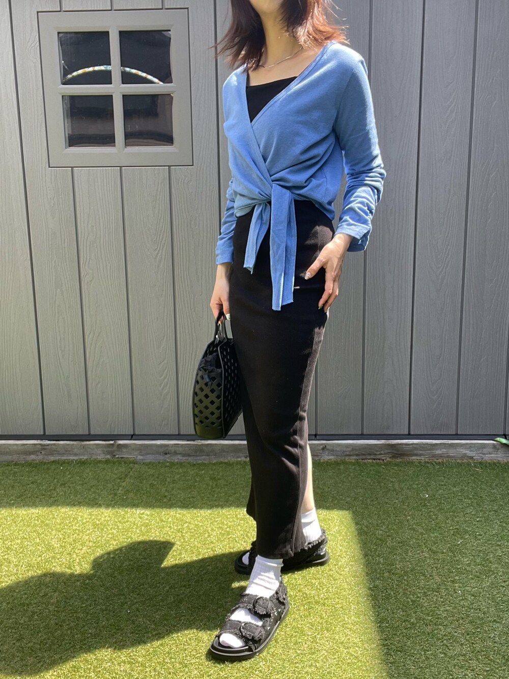ブルー系のカーディガン/ボレロ、ブラック系のワンピース、ブラック系のサンダルを着用したレディースの春コーディネートの2枚目の写真