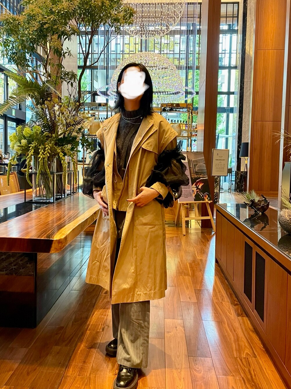 ベージュ系のトレンチコート、グレー系のニット/セーター、グレー系のスラックスを着用したレディースの冬コーディネートの2枚目の写真