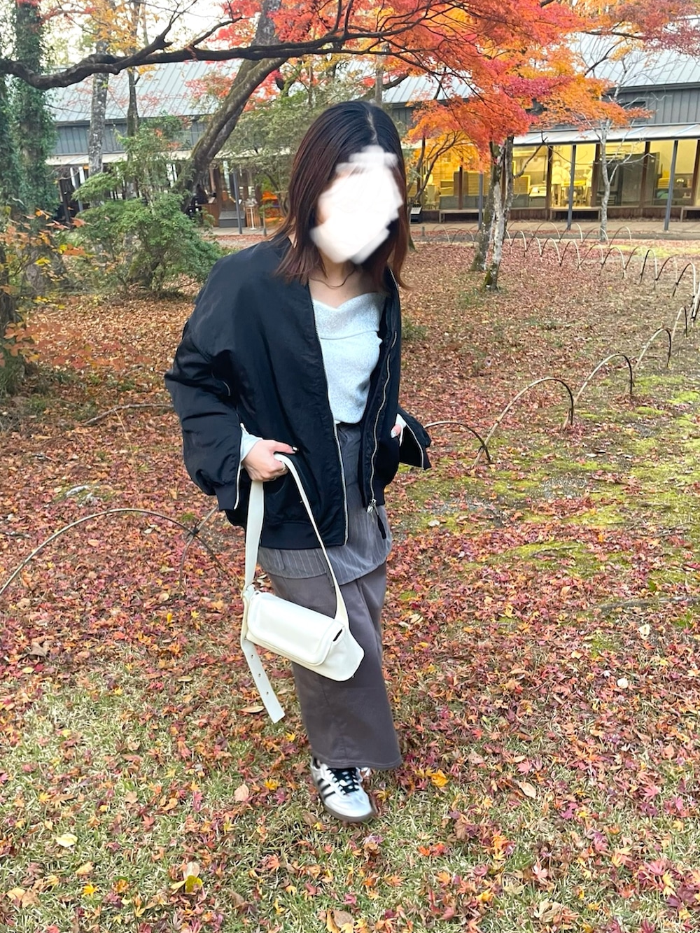 ブラック系のMA-1、シルバー系のトップス、グレー系のスラックスを着用したレディースの冬コーディネートの2枚目の写真