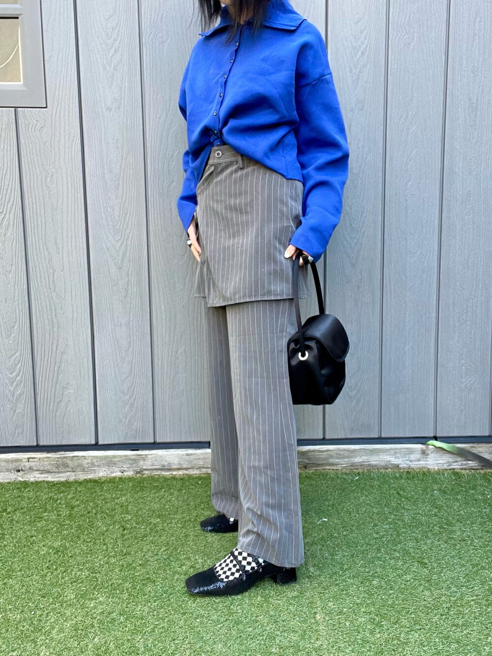 ブルー系のニット/セーター、グレー系のスラックス、ブラック系のハンドバッグを着用したレディースの冬コーディネートの2枚目の写真