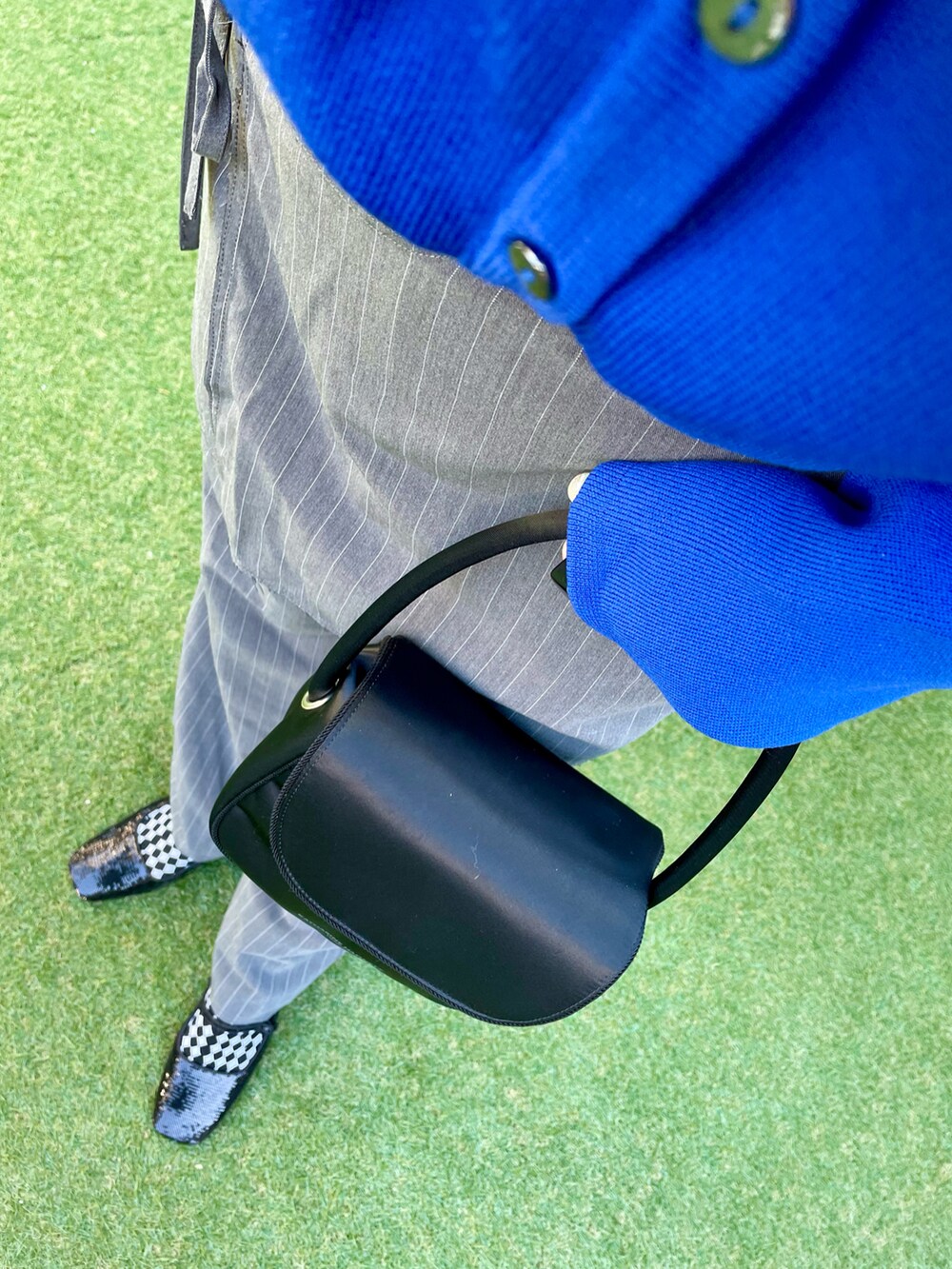 ブルー系のニット/セーター、グレー系のスラックス、ブラック系のハンドバッグを着用したレディースの冬コーディネートの3枚目の写真