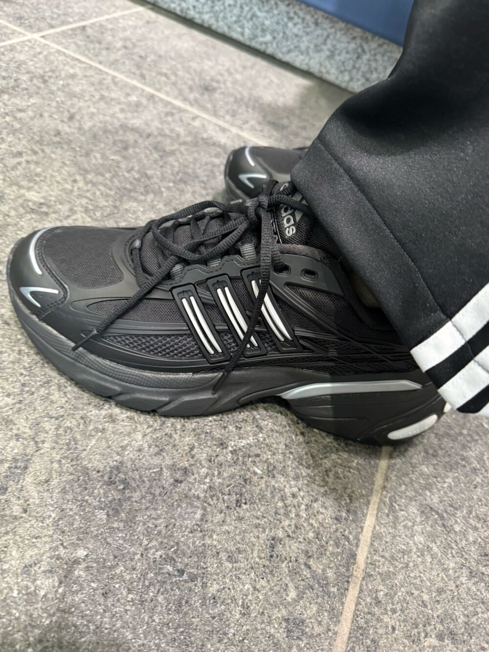 ブラック系のスニーカー、ブラック系のスウェットパンツ、グリーン系のポロシャツを着用したメンズの冬コーディネートの2枚目の写真