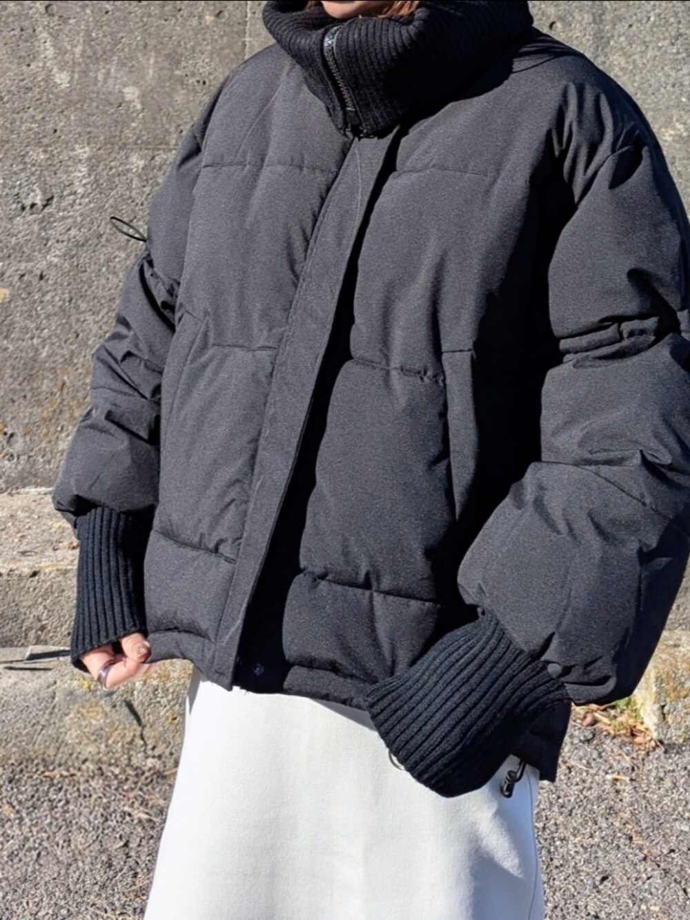 ブラック系のダウンジャケット/コート、ベージュ系のブーツ、ホワイト系のスカートを着用したレディースの冬コーディネートの3枚目の写真