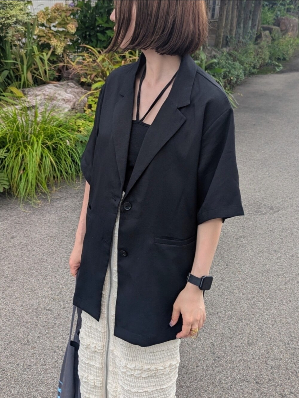 ブラック系のテーラードジャケット、ホワイト系のスカート、ブラック系のキャミソールを着用したレディースの夏コーディネートの3枚目の写真