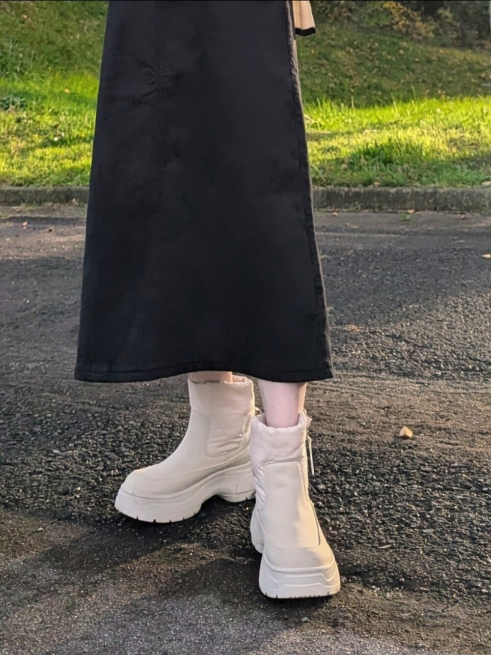 ホワイト系のニット/セーター、ブラック系のスカート、ベージュ系のノーカラーコートを着用したレディースの秋コーディネートの5枚目の写真