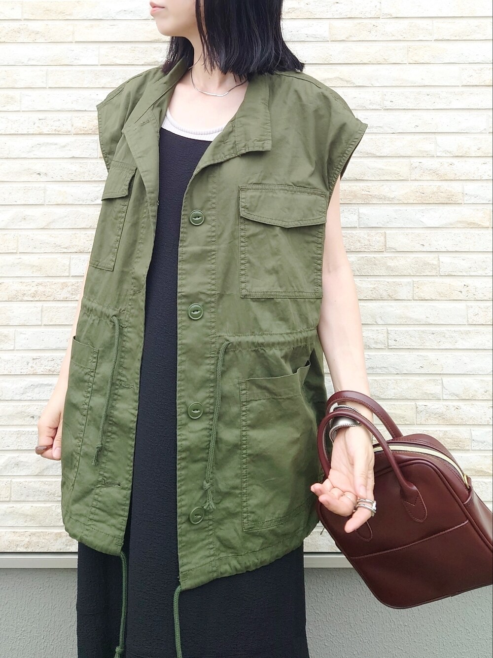 ブラック系のワンピース、グリーン系のベスト、ブラック系のサンダルを着用したレディースの夏コーディネートの2枚目の写真