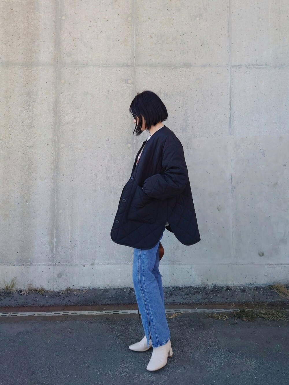 ベージュ系のスウェット、ブラック系のノーカラージャケット、ホワイト系のブーツを着用したレディースの冬コーディネートの2枚目の写真