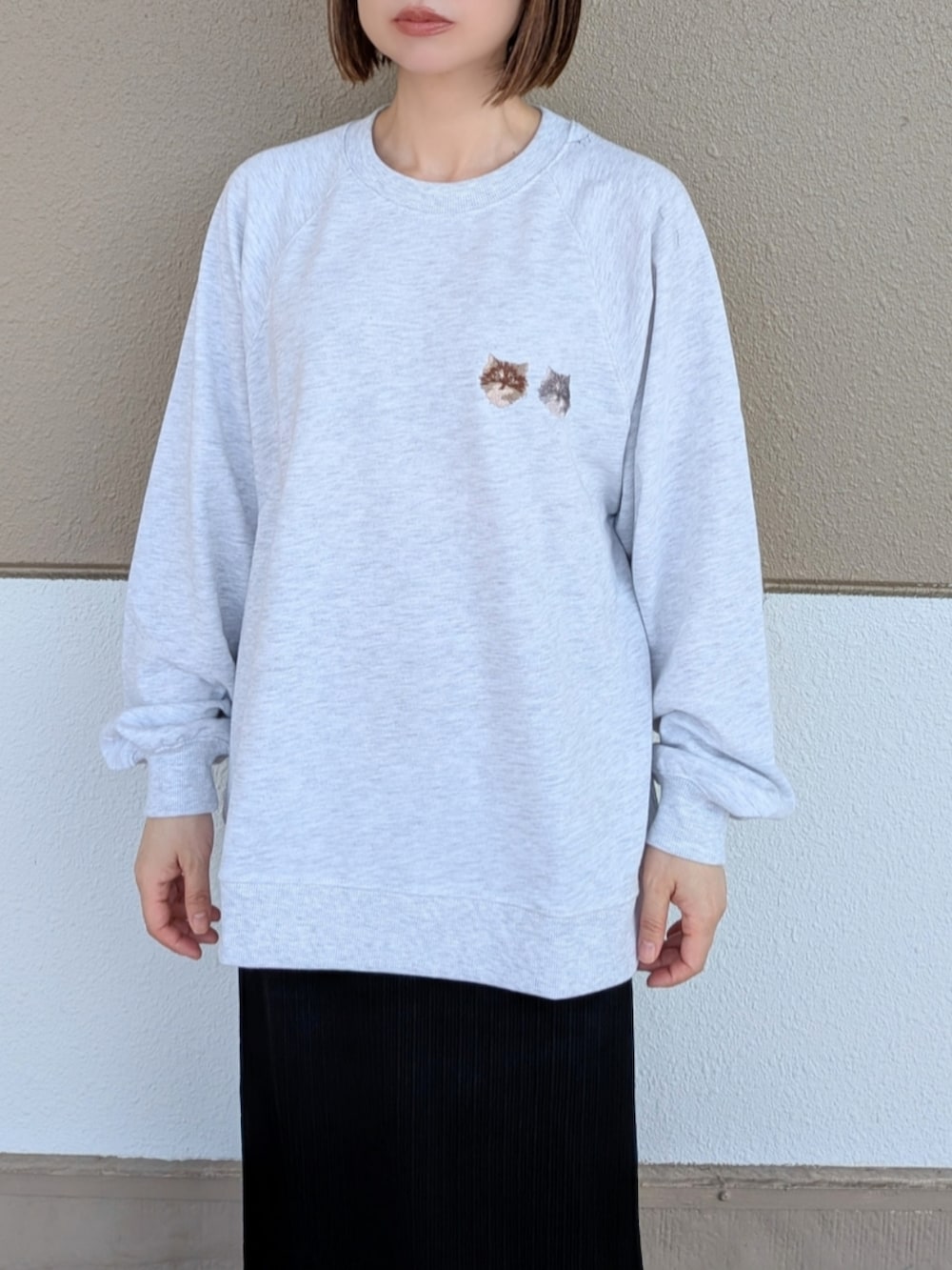 ベージュ系のスウェット、グレー系のトートバッグ、ブラック系のスカートを着用したレディースの秋コーディネートの3枚目の写真