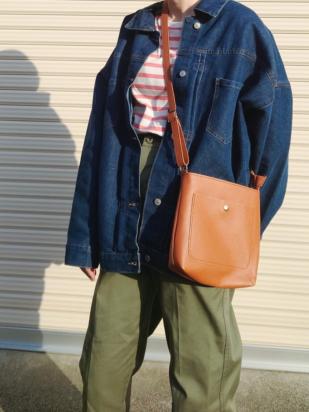 グリーン系のチノパンツ、ブラウン系のショルダーバッグ、グリーン系のパンプスを着用したレディースの冬コーディネートの3枚目の写真