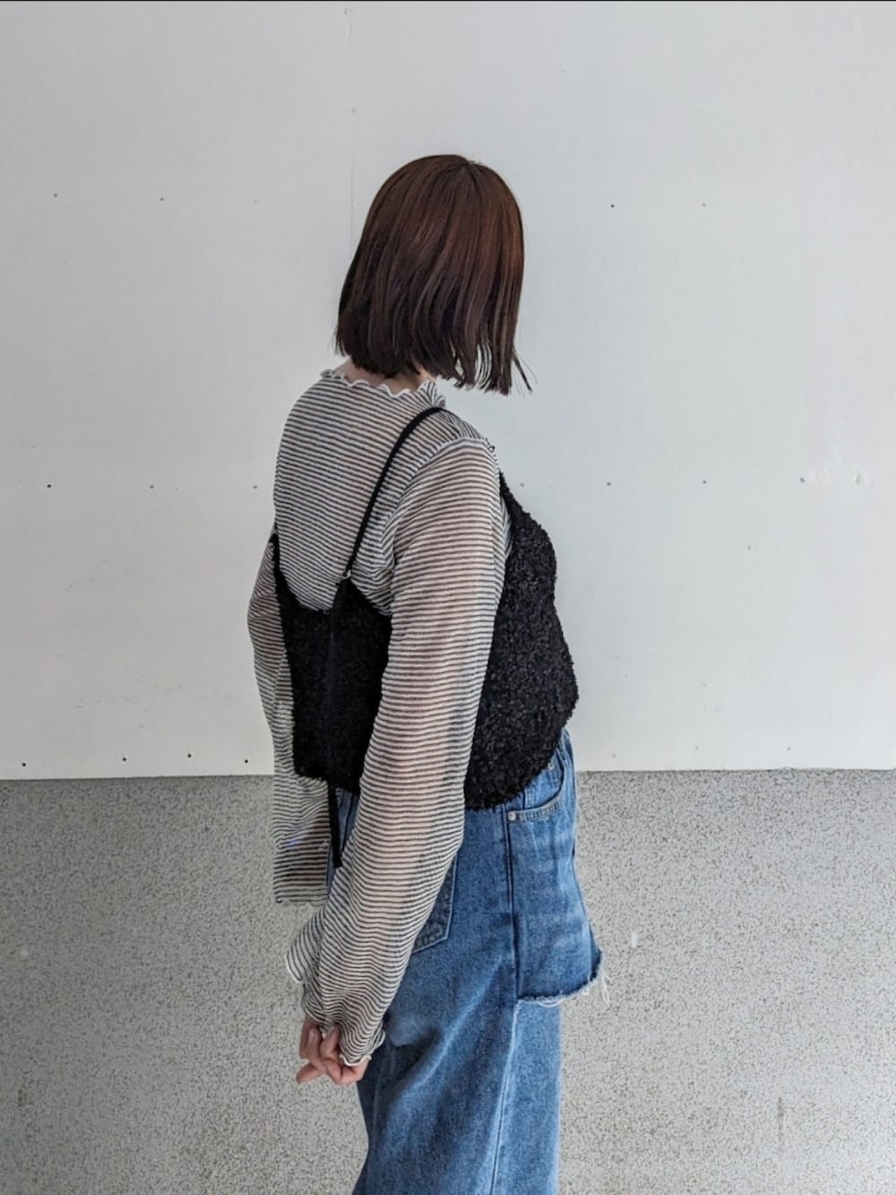 ブラック系のベスト、ホワイト系のTシャツ/カットソー、ブルー系のデニムパンツを着用したレディースの春コーディネートの2枚目の写真