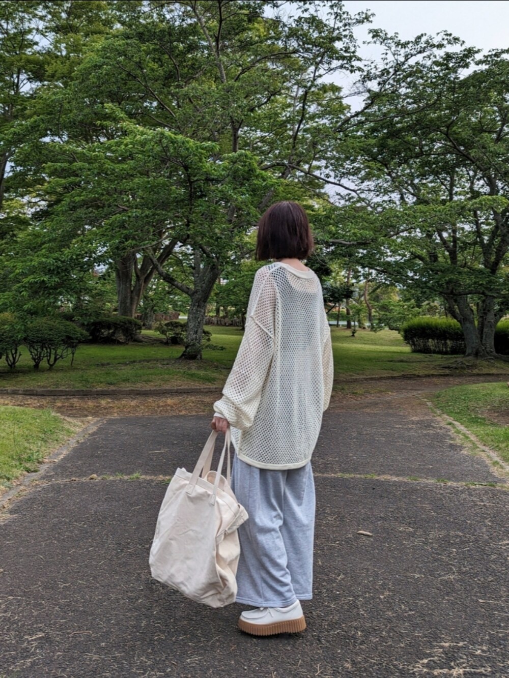 ホワイト系のニット/セーター、グレー系のスウェットパンツ、ベージュ系のショルダーバッグを着用したレディースの春コーディネートの2枚目の写真