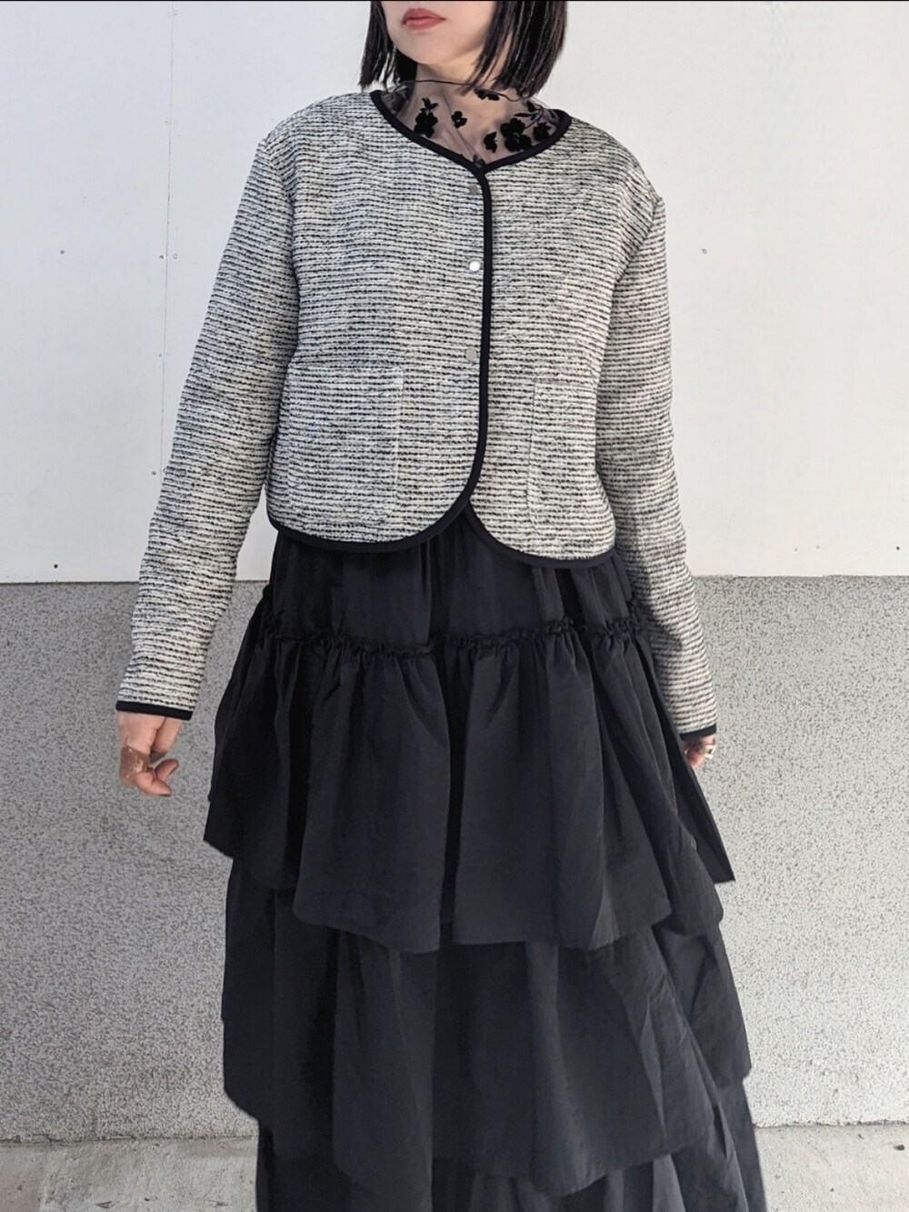 ホワイト系のノーカラージャケット、ブラック系のスカート、ブラウン系のその他トップスを着用したレディースの冬コーディネートの3枚目の写真