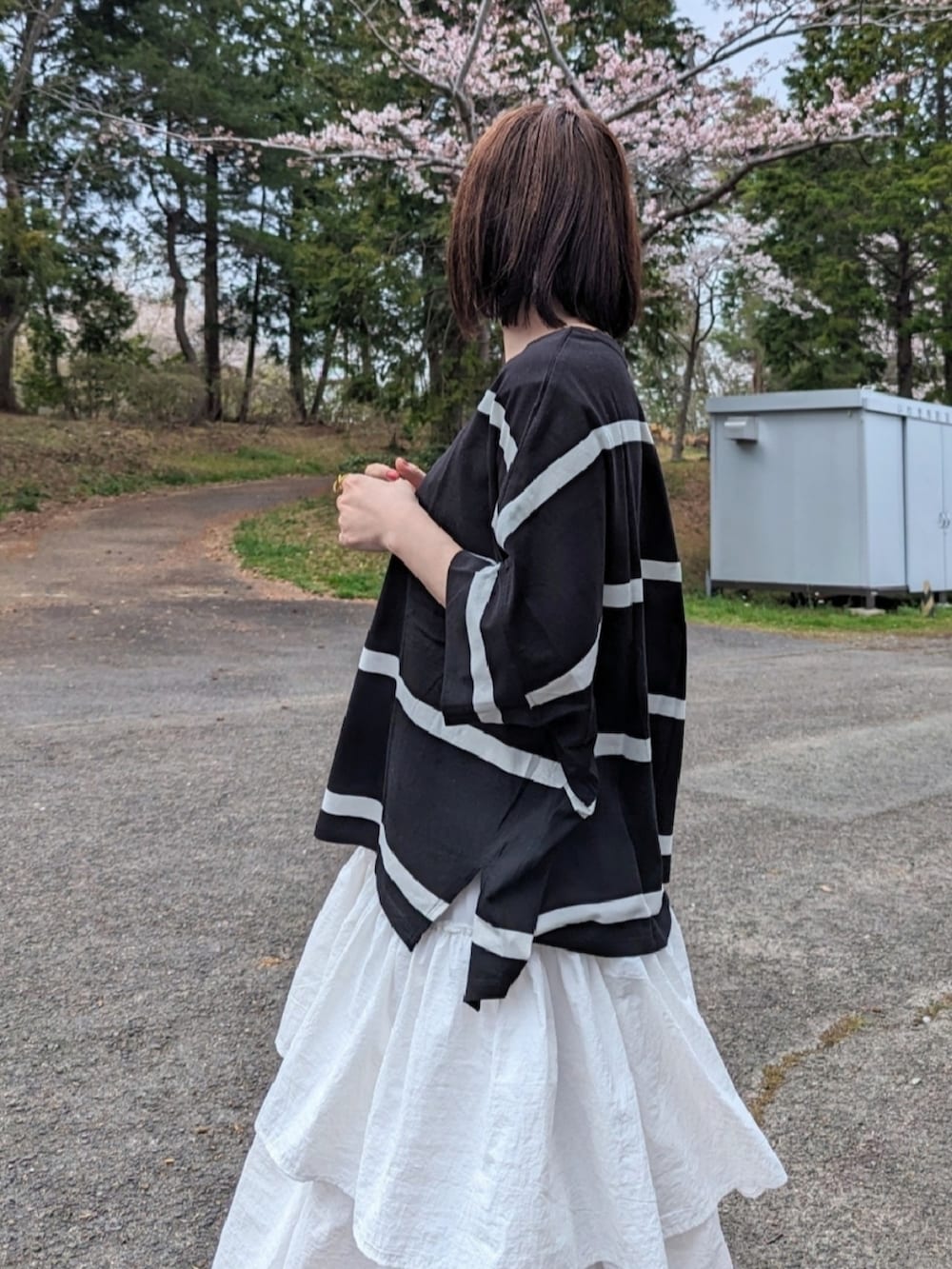 ブラック系のTシャツ/カットソー、ホワイト系のスカート、ベージュ系のスニーカーを着用したレディースの春コーディネートの3枚目の写真