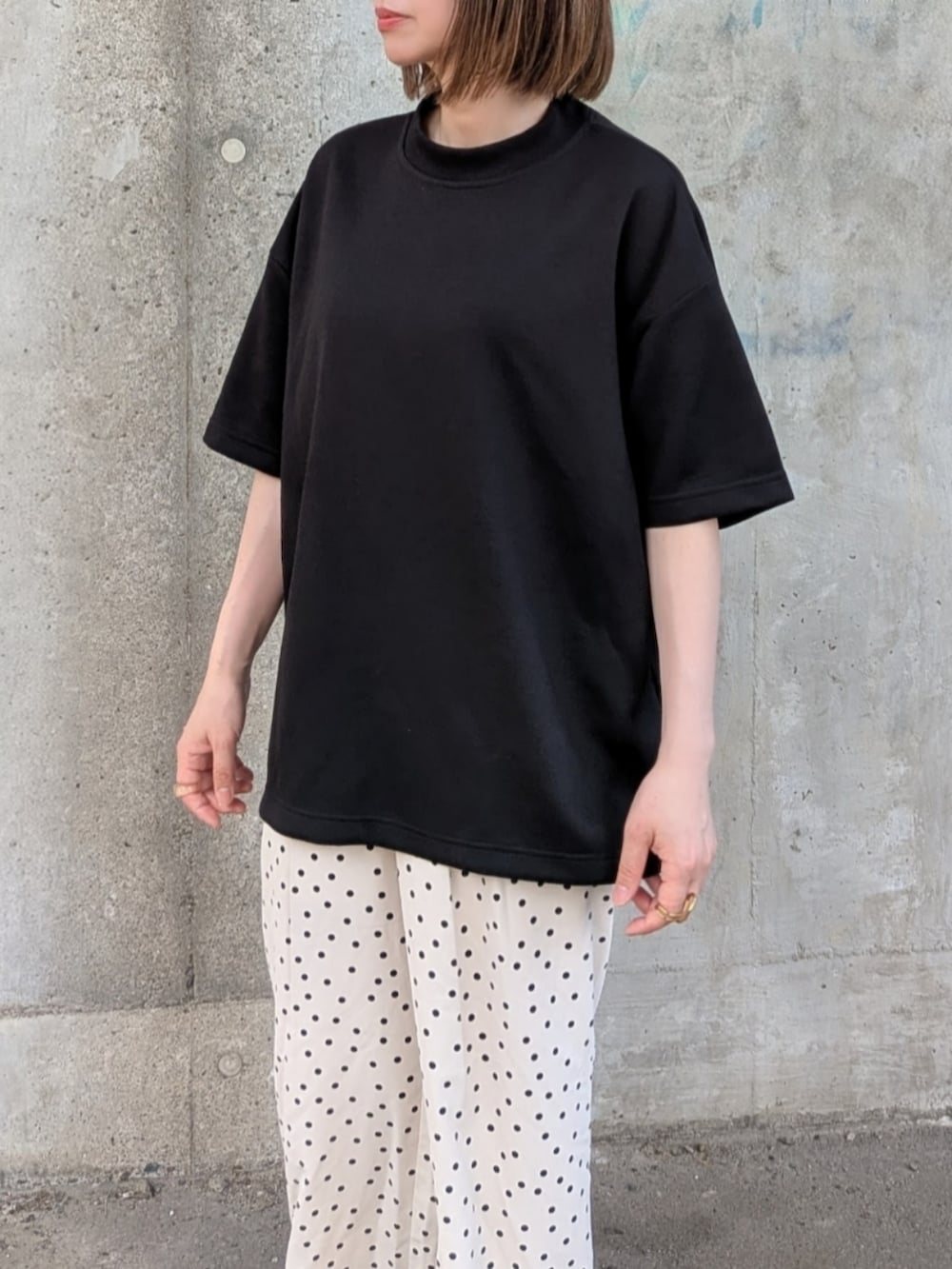 ブラック系のTシャツ/カットソー、ブラック系のトートバッグ、ホワイト系のパンツを着用したレディースの夏コーディネートの2枚目の写真