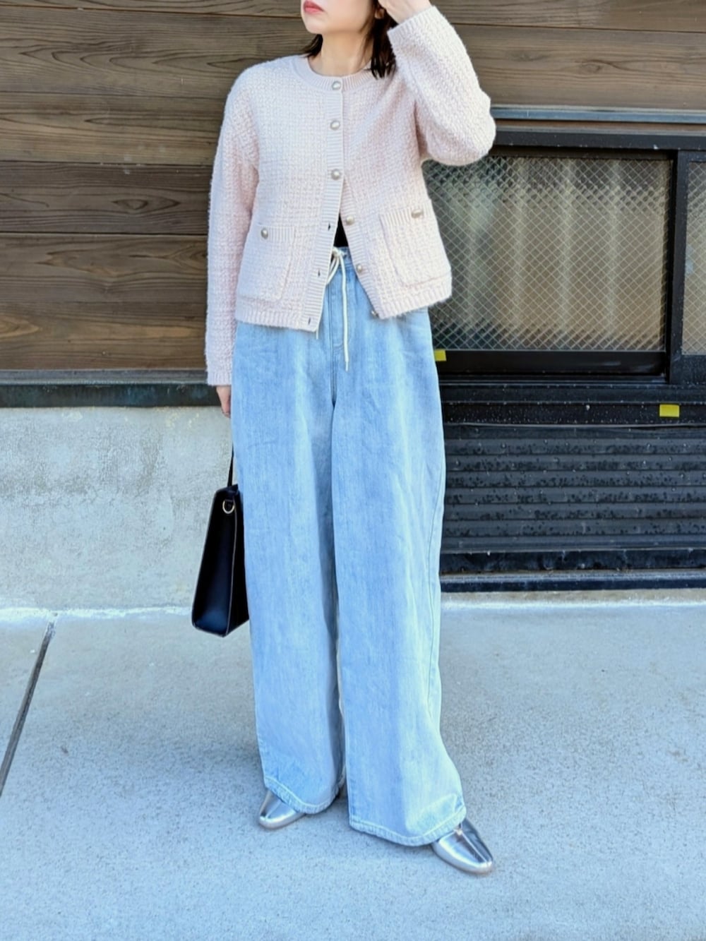 ブルー系のデニムパンツ、ブラック系のショルダーバッグ、ピンク系のカーディガン/ボレロを着用したレディースの春コーディネートの2枚目の写真