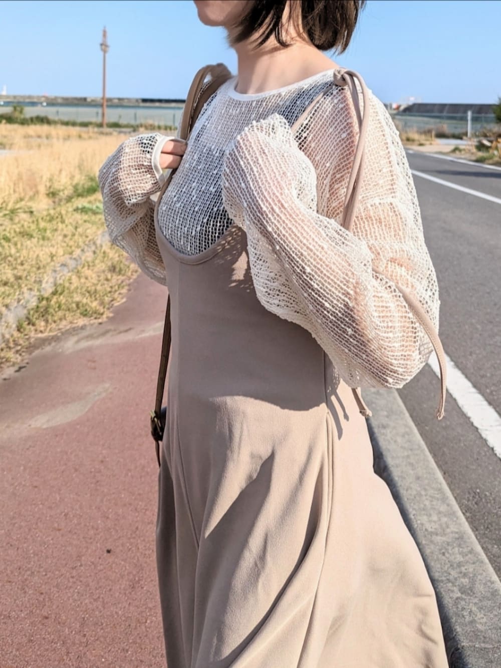 ベージュ系のワンピース、ブラウン系のショルダーバッグ、ブラウン系のブーツを着用したレディースの春コーディネートの2枚目の写真