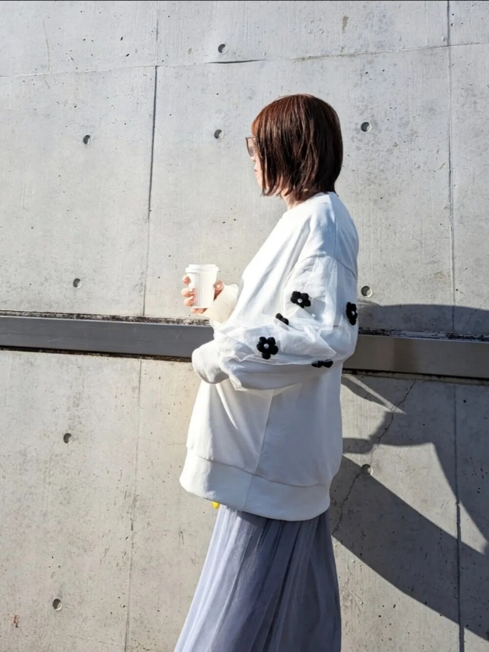 ホワイト系のスウェット、グレー系のスカート、イエロー系のショルダーバッグを着用したレディースの春コーディネートの2枚目の写真